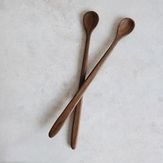 two wooden spoons sitting next to each other on a white counter top, one is empty