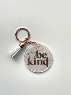 a keychain that says be kind with a tassel hanging from it's end