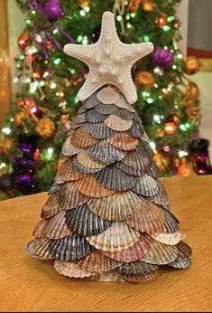 a christmas tree made out of seashells on top of a wooden table next to a christmas tree