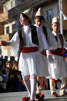 some people are walking down the street in white dresses and red shoes while others watch