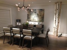 a dining room table with white chairs and a painting on the wall