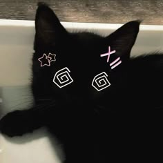 a black cat laying in a sink with pink and white stickers on it's eyes