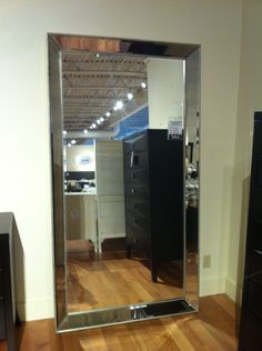 a large mirror sitting on top of a hard wood floor next to a black dresser