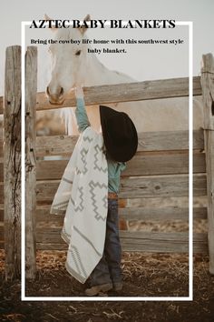 a little boy that is standing next to a fence with a horse in the background