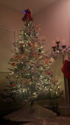 a white christmas tree with red and green ornaments in the corner next to a mirror