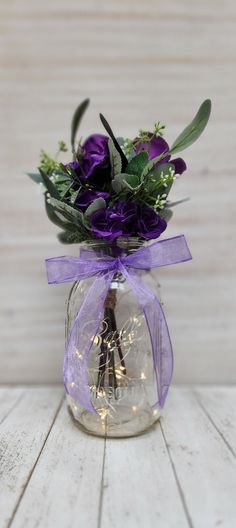 a vase with purple flowers and greenery in it