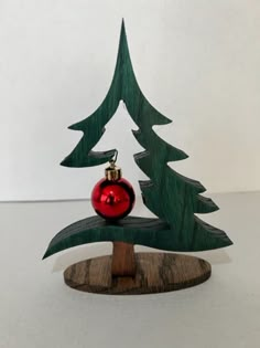 a small wooden christmas tree with a red ornament