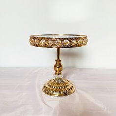 a gold colored cake stand on a white table