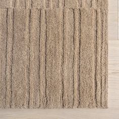 a close up of a rug on the floor with white wood floors in the background