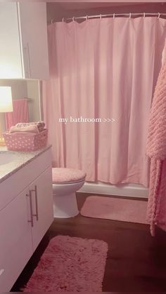 a bathroom with pink rugs and shower curtain