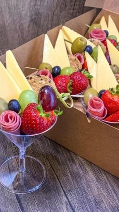 some fruit is sitting in a box on a table next to a wine glass and bag