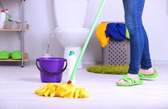 a woman is cleaning the floor with a mop and bucket in front of her