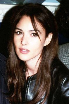 a woman with long brown hair wearing a black leather jacket and looking at the camera