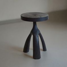 a small wooden stool sitting on top of a white floor next to a wall and window