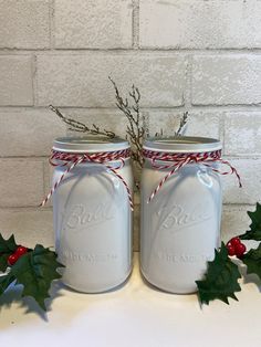 two mason jars decorated with holly and twine