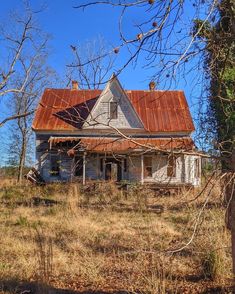 an old run down house with rusted tin roof sits in the middle of a field