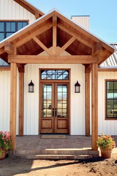 the front entrance to a white house with wood accents