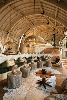 an indoor lounge area with wicker furniture and round lights hanging from the rafters