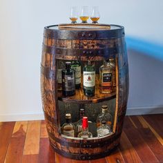 a wooden barrel filled with liquor bottles on top of a hard wood floor next to a wall