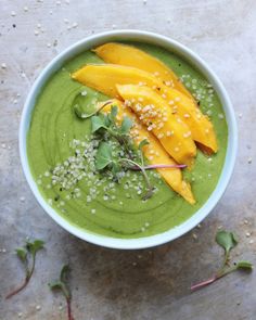 a green smoothie bowl with mangoes and sprinkles