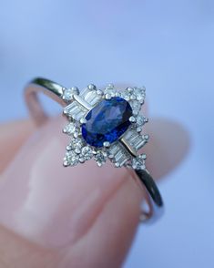 a woman's hand holding a ring with a blue and white stone in it