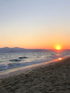 the sun is setting over the ocean and beach