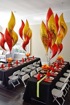 a room filled with lots of tables covered in black table cloths and red and yellow balloons