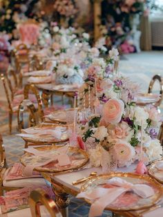 the tables are set up with pink and white floral centerpieces, gold chairs, and place settings