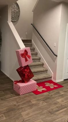 two wrapped presents sitting on the floor in front of stairs with red bows and ribbons