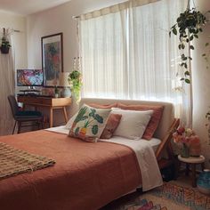 a bed sitting in a bedroom next to a window covered with curtains and plants on top of it