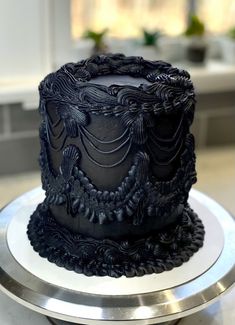 a black frosted cake sitting on top of a silver plate