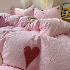 a bed with pink sheets and pillows has a heart drawn on the comforter in front of it