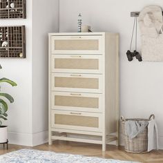 a white dresser sitting next to a plant in a living room on top of a rug