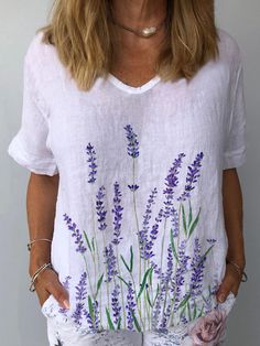 a woman in white shirt with purple flowers painted on her chest and jeans rolled up