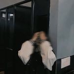 a blurry image of a person in a public bathroom stall with his hands on his head