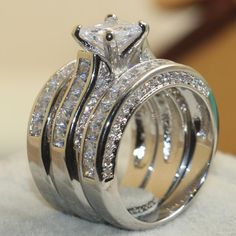 a wedding ring set with three rows of diamonds on top of each other, sitting on a white cloth