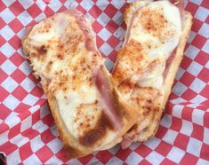 two slices of ham and cheese sandwich on a red and white checkered paper