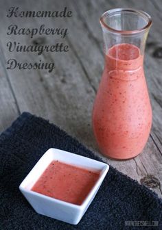 homemade raspberry vinaggete dressing in a small white bowl next to a glass pitcher