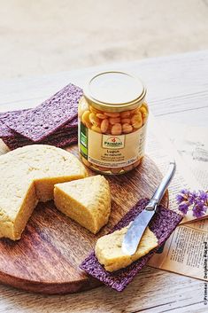 a wooden plate topped with crackers next to a jar of peanut butter