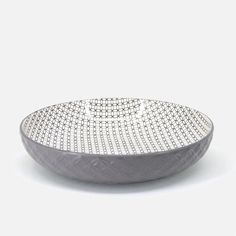 a white and grey bowl on a white surface with small circles in the center, set against a plain background