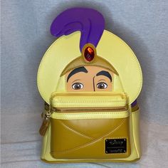 a yellow purse with an evil woman's head sticking out of the front pocket