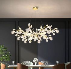 a chandelier hanging over a dining room table with four chairs and a potted plant