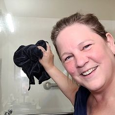 a woman holding up a black cloth in front of her face and smiling at the camera