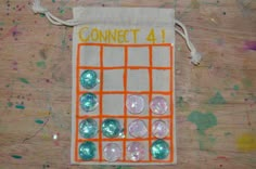 an orange and white bag with buttons on it sitting on a wooden table next to paint splatters