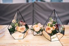 three geometric glass vases with flowers in them