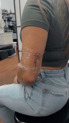 a woman sitting on top of a stool with a tattoo on her arm