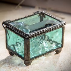 a green glass box sitting on top of a marble counter next to a light bulb