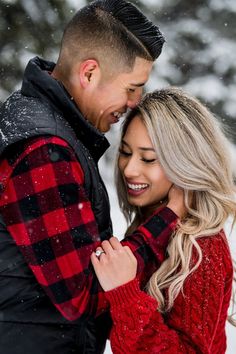 a man and woman standing in the snow with their hands on each other's shoulders