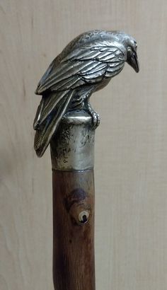 a metal bird sitting on top of a wooden pole