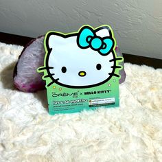 a hello kitty sticker sitting on top of a white fluffy blanket next to a rock